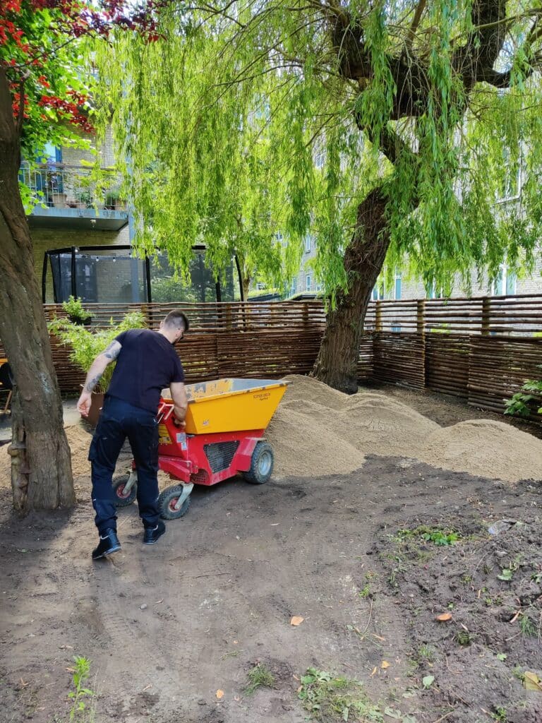 Grus til kunstgræs bliver lagt på den opgravede have.